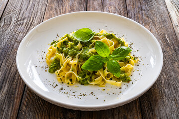 Tagliatelle with basil pesto sauce on wooden table
