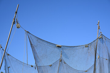 Hanging fishing nets against a clear blue sky in a harbor at the Baltic sea, concept for maritime vacations and fishing industry, copy space