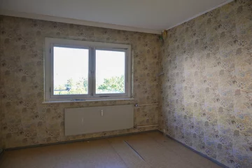 Fotobehang Unrenovated empty room with an old patterned wallpaper on the walls, concept for housing and shortage of affordable living space, copy space © Maren Winter