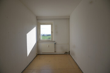 Narrow unrenovated room with heater and window, concept for housing shortage and small space living...