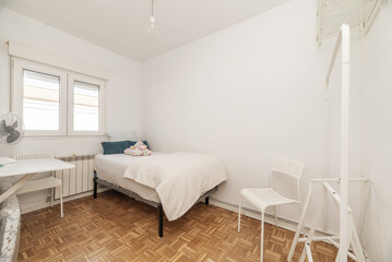 Bedroom with a single bed with a donkey-type wardrobe and slatted parquet floors arranged in a chessboard pattern and a folding desk table