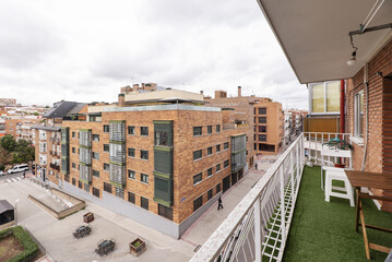 Views of buildings on a block with pedestrian crossings from a terrace with artificial grass floors