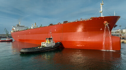 Tug boats assisting big oil tanker. Large oil tanker ship enters the port escorted by tugboats. © dechevm