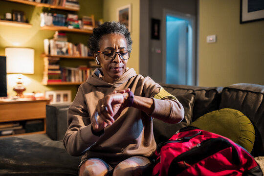 Senior African American woman checking her smartwatch at home before going out to exercise