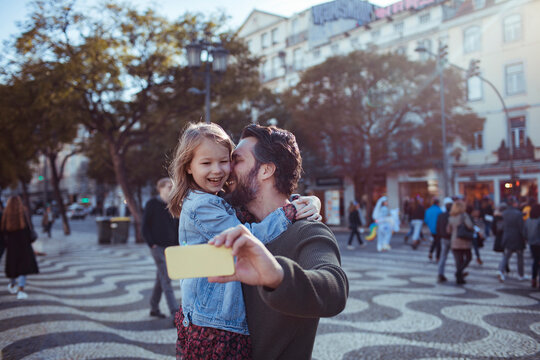 Happy young father taking selfies with his daughter in the Rossio Square