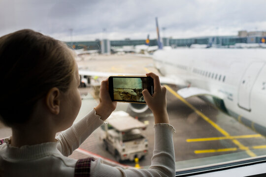 Young girl taking pictures of a airplane on the smartphone in the airport
