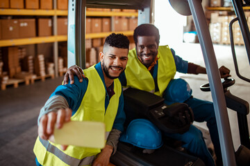 Two African American workers taking selfies in a warehouse