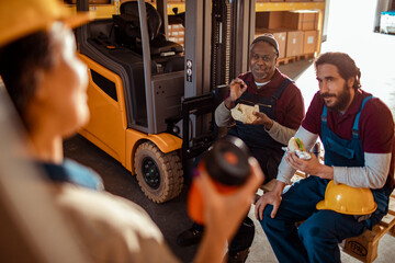 Two diverse male colleagues having lunch together on break from working in a warehouse