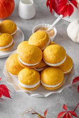 Pumpkin sandwich cookies with cream cheese on a gray concrete bsckground. Spicy autumn dessert. Copy space.