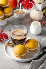 Pumpkin sandwich cookies with cream cheese on a gray concrete bsckground. Spicy autumn dessert. Copy space.