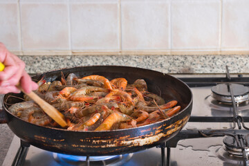 Shrimp frying in a pan on a gas flame