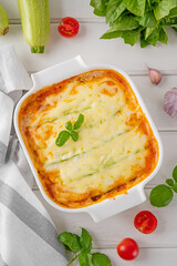 Delicious zucchini lasagna with sauce bolognese in a baking dish on a white wooden bachground. Healthy food. Top view. Selective focus.