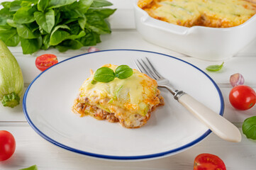 Delicious zucchini lasagna with sauce bolognese on a plate on a white wooden bachground. Healthy food. Top view. Selective focus.