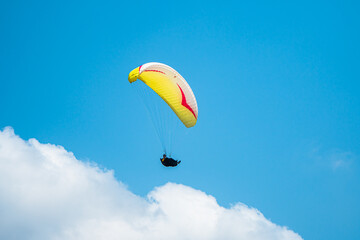 An adrenaline-pumping extreme sport, paragliding against the clear blue sky. Paraglider flying with...