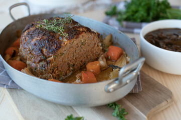 Pork meatloaf with vegetables and dark onion sauce on a table
