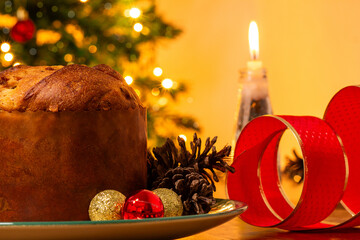 Um panetone sobre a mesa com decoração natalina ao redor. © Angela