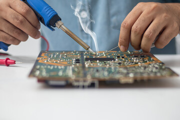 Technician using a soldering iron to repair a circuit board