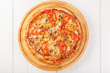 delicious pizza with chicken, mushrooms, cheese, tomatoes and corn on a wooden background