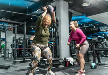 Two plus-size women workout and exercise with medicine ball at the gym. They're determined to achieve their goals and inspire others along the way.	 - Powered by Adobe