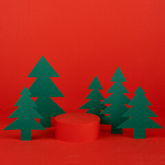 Festive Christmas stage with red cylinder podium mockup with green spruces as forest for...