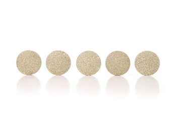 Round tablets in a row. Multiple green textured pressed wafer tablets or pills. Isolated multivitamins for dogs, food supplement. Selective focus. White background.