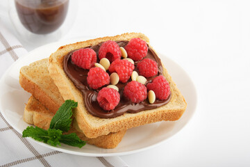 Sweet sandwich with raspberries and chocolate paste on a plate. Copyspace.