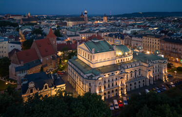 Krakow, Poland, aerial view of City Theatre (Slowacki) and Holy Cross church with old town illuminated during blue hour