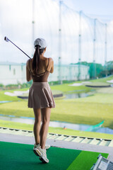 Woman play golf in the driving range