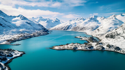 Fototapeta na wymiar Aerial view of a turquoise mountain lake, surrounding greenery, snow - capped mountains in the distance