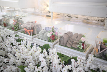 Acrylic gift boxes at Indonesian wedding receptions are placed on the wedding floor with white plastic flowers.