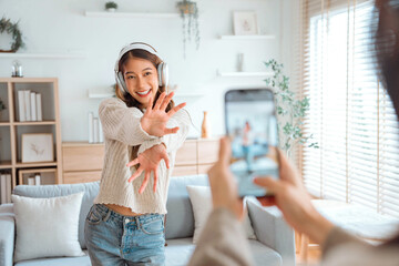 Happy young asian vlogger influencer woman with her friend cover dancing video by smartphone camera together, To share video on social media - obrazy, fototapety, plakaty
