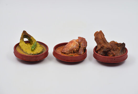 HILSHA FISH,PRAWN FISH, MUTTON KOSHA ON CLAY BOWN. FRONT VIEW WITH SELECTIVE FOCUS. ISOLATED ON WHITE BACKGROUND.