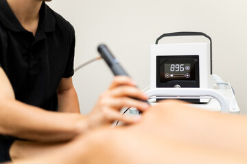 Photo of an unrecognizable woman goes to a physiotherapy clinic to undergo shockwave therapy to...