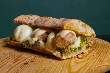 Panuozzo napoletano ripieno di friarielli, provola affumicata e polpette di carne fritte servito su...