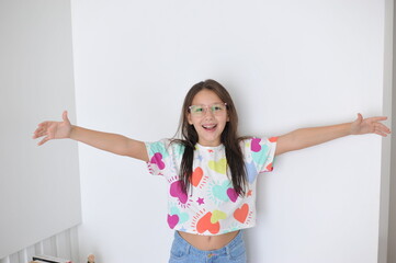 menina sorridente comemorando a vida , com camisa de corações , feliz dia das crianças  - obrazy, fototapety, plakaty