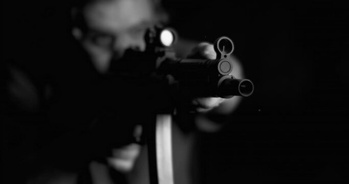 Dramatic weapon being shot in 800 fps in monochromatic, black and white. Person aiming and firing assault rifle