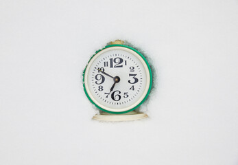 Alarm clock in the snow. Concept of approaching winter.