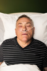 Portrait of sleeping senior man with an oxygen tube in his nose and his mouth gently open in hospital