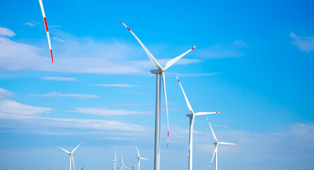 Fleet of power generators in motion. The blades of the wind farm rotate against the sky. The...