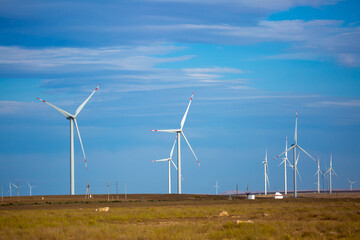 Fleet of power generators in motion. The blades of the wind farm rotate against the sky. The...