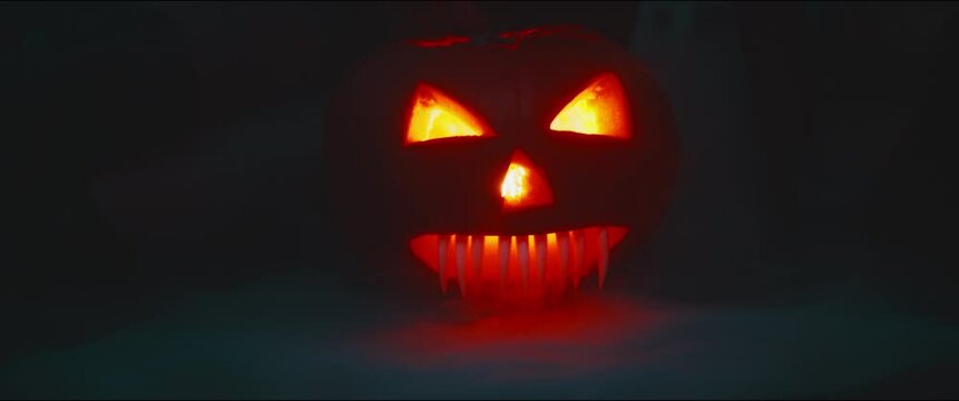 Female hand caress creepy Halloween Pumpkin with a flickering light and smoke coming out of the mounth