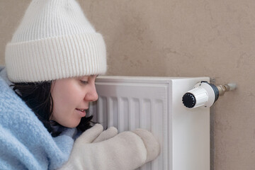 As the price of heating continues to rise, a woman in a warm outfit sits next to a radiator trying to keep warm