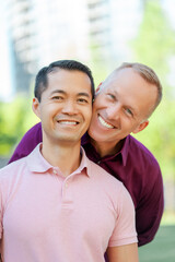 Portrait of smiling middle aged homosexual men hugging looking at camera on urban street