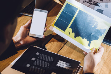 Man checking diagram and holding cellphone