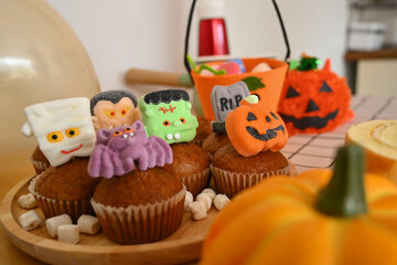 Halloween cupcakes and pumpkins on kitchen countertop. Sweets for holiday party, festive food concept