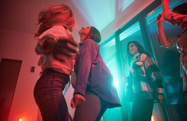 Young women having party inside contemporary barn house at night.