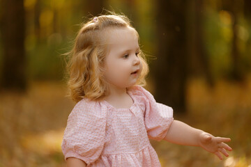 happy little child, baby girl laughing and playing in the autumn on the nature walk outdoors