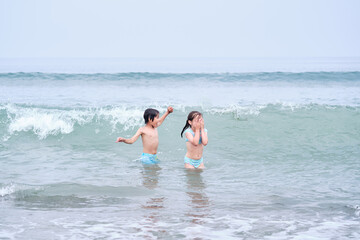 A boy and a girl are having fun playing in the sea.