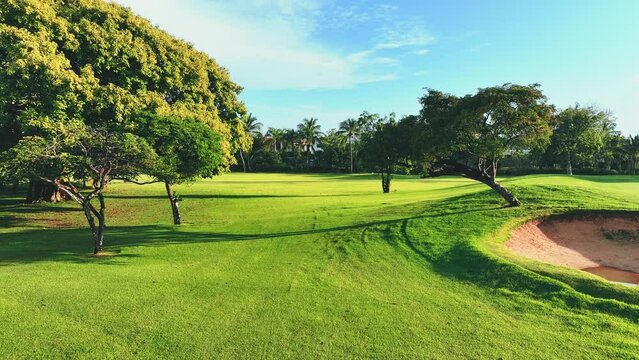 Panoramic views of the golf course. Lawn with green grass. Elite sport. Sand bunker and tropical trees. Green golf course next to the hotel. Vacation concept.