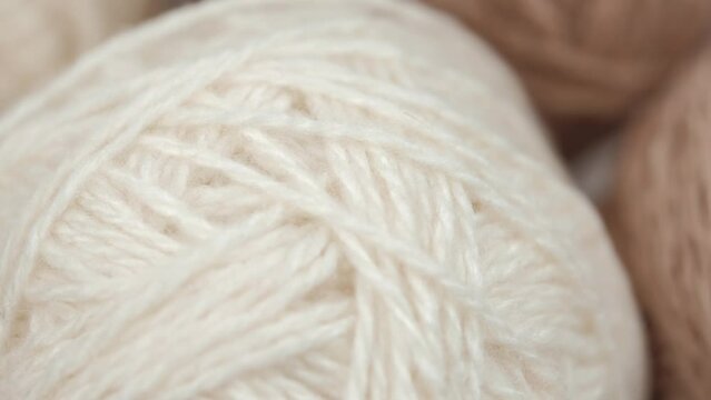 warm and cozy yarn of neutral shades for needlework. closeup rotation of balls of white and beige wool natural yarn. needlework and crocheting or knitting. leisure, hobbies. macro.